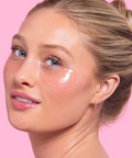 Woman with under-eye cream on a pink background