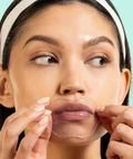 Woman applying a clear patch to her face with a light blue background