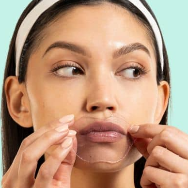 Woman applying a clear patch to her face with a light blue background
