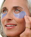 Woman applying eye patches to her face