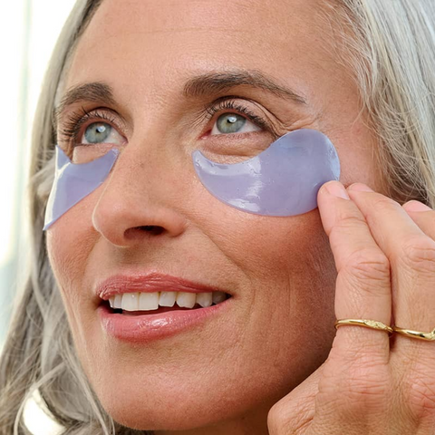 Woman applying eye patches to her face