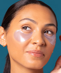 Woman wearing pink eye patches against a blue background