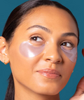 Woman wearing pink eye patches against a blue background