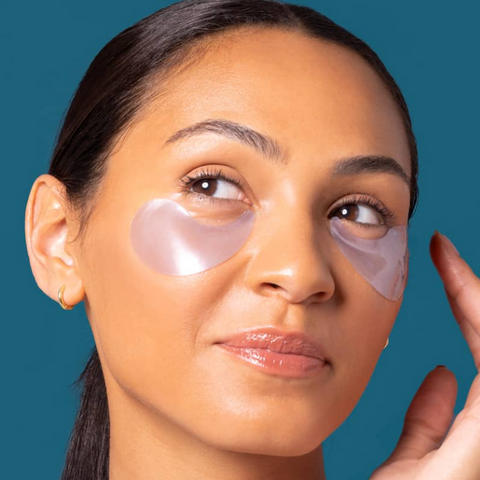 Woman wearing pink eye patches against a blue background