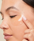 Person applying cream to their face with a neutral background