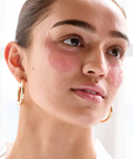 Woman wearing pink eye patches on a white background