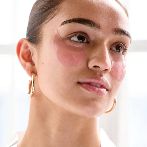 Woman wearing pink eye patches on a white background