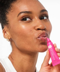 Woman applying pink lip balm labeled 'Lip Service' on a white background