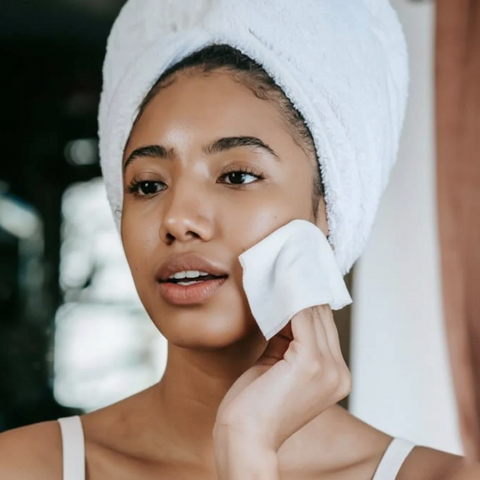 Woman applying a facial mask with a towel on her head
