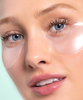 Close-up of a person wearing clear eye patches on a light green background