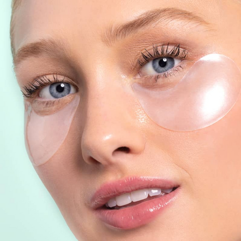 Close-up of a person wearing clear eye patches on a light green background