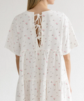 White floral dress with a lace-up back worn by a model on a white background