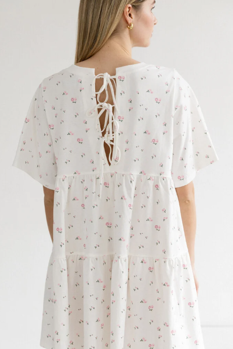 White floral dress with a lace-up back worn by a model on a white background