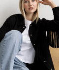 Woman wearing a black fringe jacket with product details on a website page.