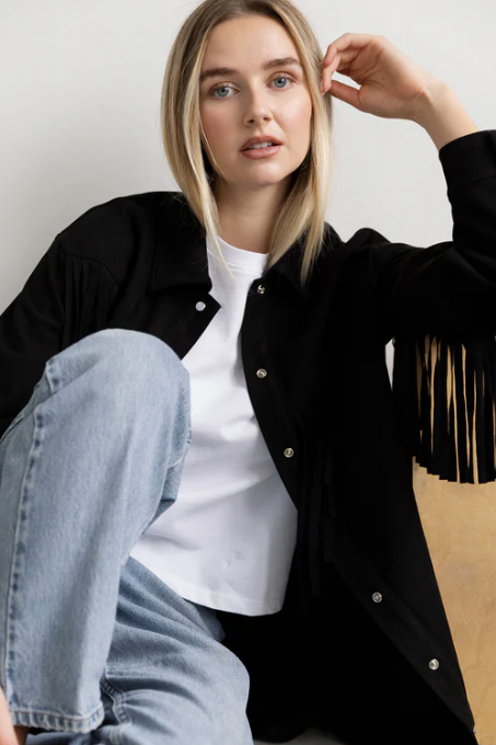 Woman wearing a black fringe jacket with product details on a website page.