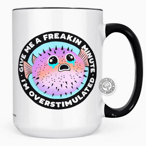 White mug with black handle featuring a colorful puffer fish graphic and text on a white background.