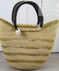 Woven straw bag with black handles on a light wooden floor.