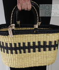 Person holding a woven basket with black and beige pattern