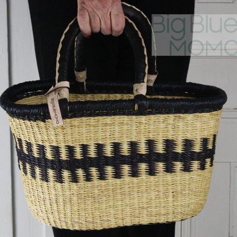 Person holding a woven basket with black and beige pattern