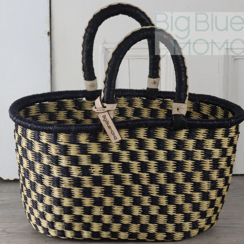 Woven basket with black and beige pattern on a wooden surface
