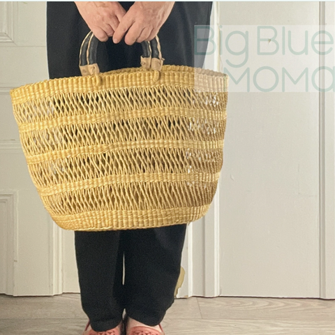 Person holding a woven basket with 'Big Blue Momo' branding in the background