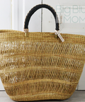 Woven straw tote bag with black handle on a white background