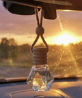 Car air freshener shaped like a crystal hanging from a car's rearview mirror with a sunset in the background.