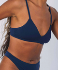 Navy blue bikini top worn by a person on a white background