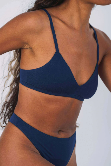 Navy blue bikini top worn by a person on a white background