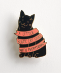 Black cat-shaped pin with pink ribbon and text on a white background