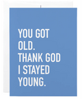 Blue card with white text 'YOU GOT OLD. THANK GOD I STAYED YOUNG.' on a white background