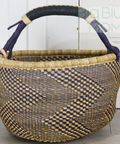 Woven basket with a checkered pattern and purple handles on a light wooden floor.
