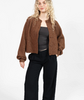 Woman wearing a brown jacket and black pants on a white background