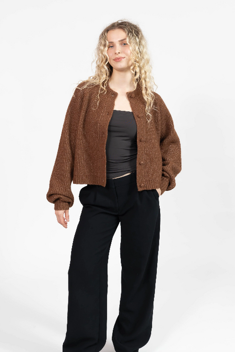 Woman wearing a brown jacket and black pants on a white background