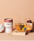 Tea canister labeled 'tease' with a glass of tea and cherries on a beige background