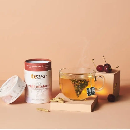 Tea canister labeled 'tease' with a glass of tea and cherries on a beige background