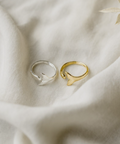 Two rings, one gold and one silver, on a soft fabric background