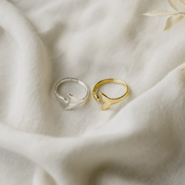 Two rings, one gold and one silver, on a soft fabric background