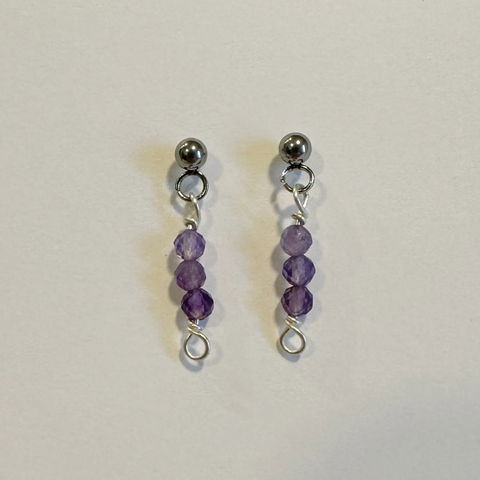 Pair of purple beaded earrings on a light gray background