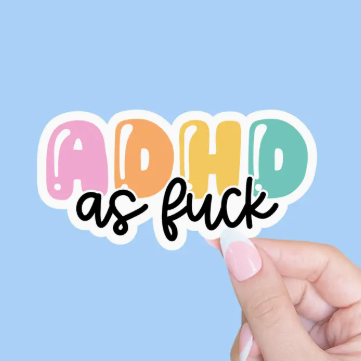 Colorful 'ADHD as fuck' sticker held by a hand against a light blue background