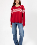 Woman wearing a red sweater with white stripes and blue jeans on a white background