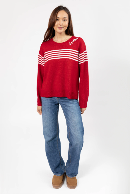 Woman wearing a red sweater with white stripes and blue jeans on a white background