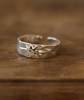 Silver ring with tree design on a wooden surface