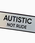 Rectangular sign with 'AUTISTIC NOT RUDE' text on a white background