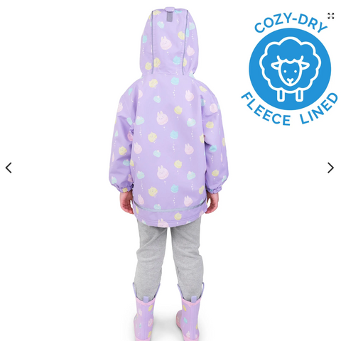 Child wearing a purple raincoat with sheep pattern and gray pants, standing against a white background with Cozy-Dry logo.