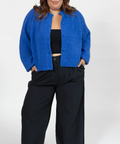Person wearing a blue cardigan over a black top and pants on a white background