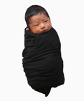 Newborn baby wrapped in a black swaddle on a white background
