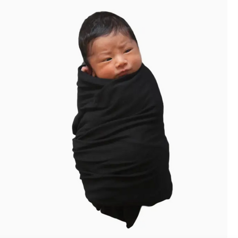 Newborn baby wrapped in a black swaddle on a white background