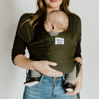 Woman holding a baby in a green baby carrier with a plain background