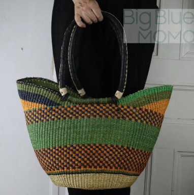 Woven bag with green and orange stripes held by a person against a plain background
